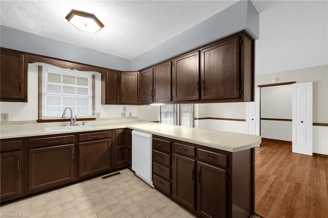 kitchen with kitchen peninsula, dishwasher, sink, and dark brown cabinetry