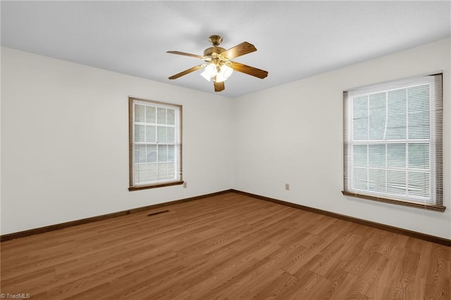 empty room with ceiling fan, wood-type flooring, and a wealth of natural light