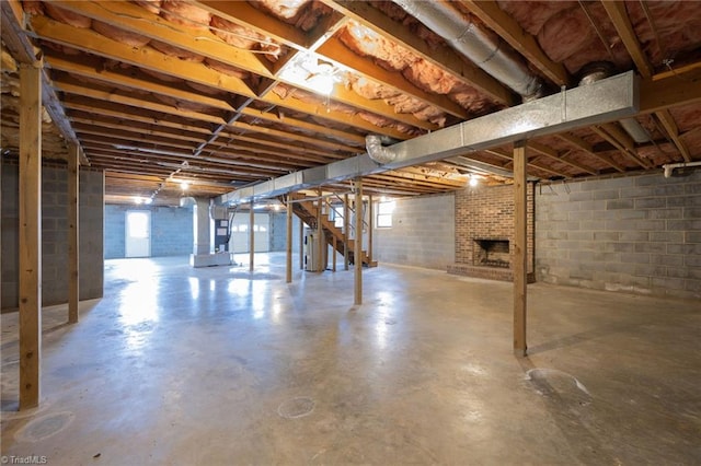 basement with heating unit, plenty of natural light, water heater, and a brick fireplace