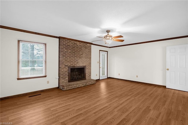 unfurnished living room with ceiling fan, hardwood / wood-style floors, crown molding, and a brick fireplace