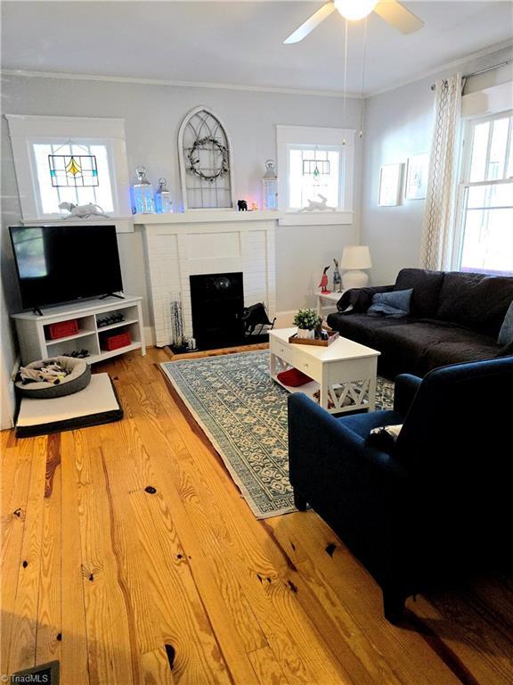 living area featuring ornamental molding, a fireplace, ceiling fan, and wood finished floors