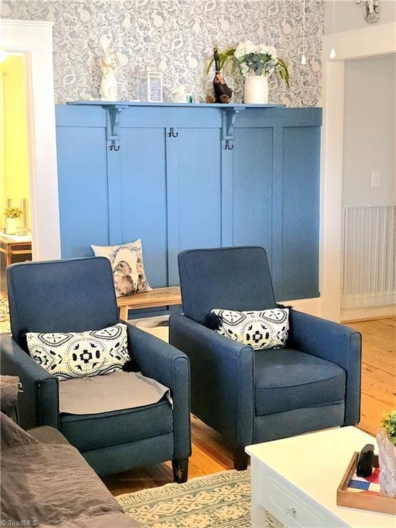 living area with light wood-type flooring, a wainscoted wall, and wallpapered walls