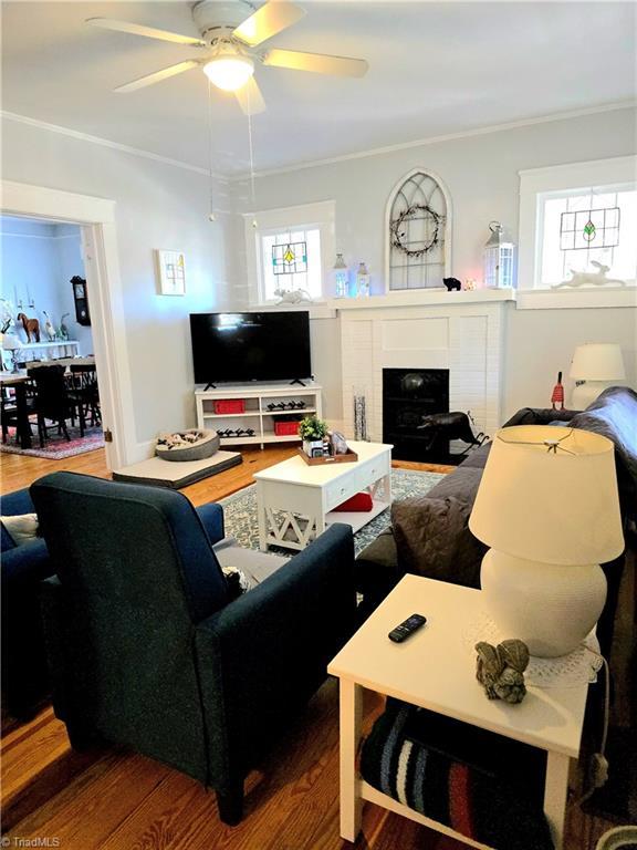 living room with ceiling fan, ornamental molding, a fireplace, and wood finished floors