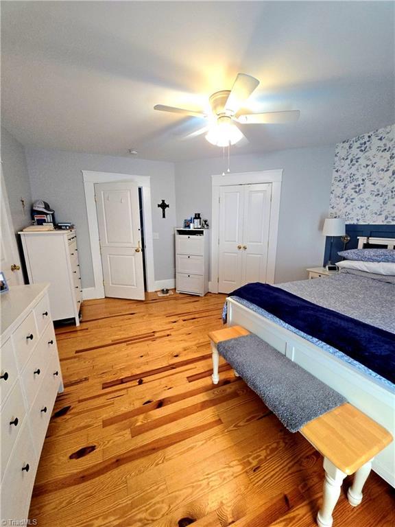 bedroom featuring baseboards, a closet, a ceiling fan, and light wood-style floors