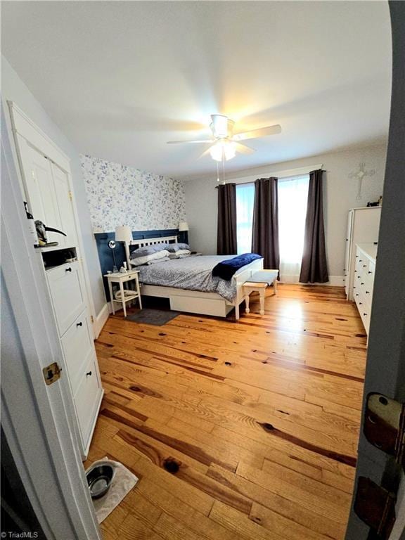 bedroom featuring wallpapered walls, light wood-style flooring, baseboards, and ceiling fan