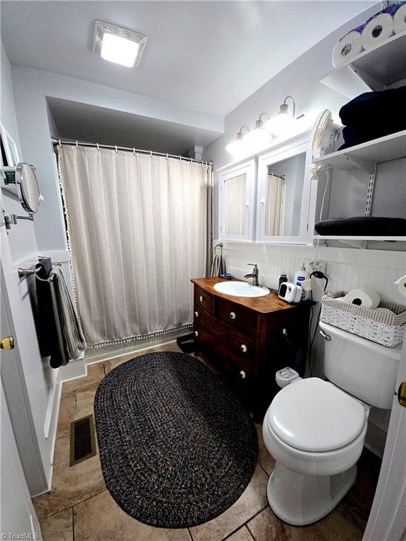 full bath featuring toilet, vanity, visible vents, and a shower with shower curtain