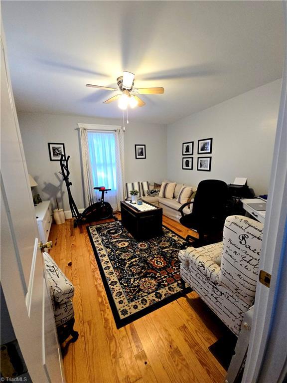 living area with wood-type flooring and a ceiling fan