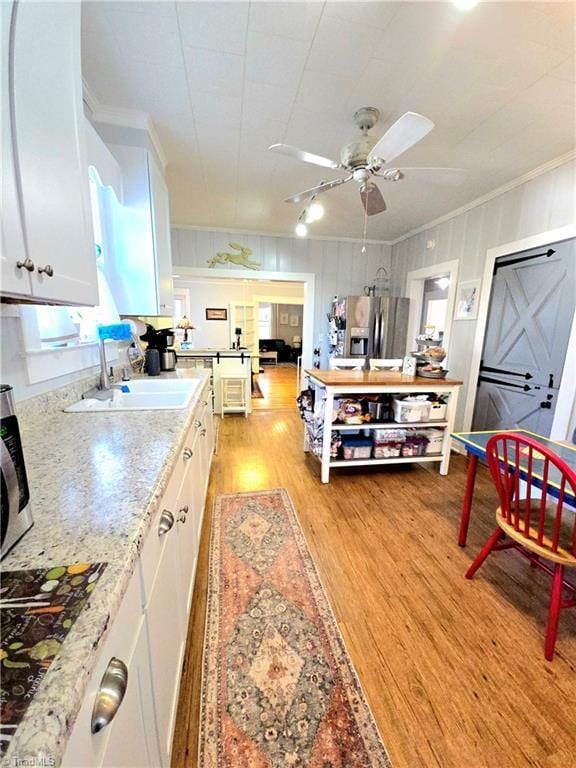 kitchen with ornamental molding, light wood-type flooring, white cabinetry, and stainless steel refrigerator with ice dispenser