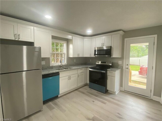 7 Crutchfield Ave, Lexington, NC 28445 - kitchen featuring stainless steel appliances, a sink, light wood-style floors, white cabinets, and light stone counters