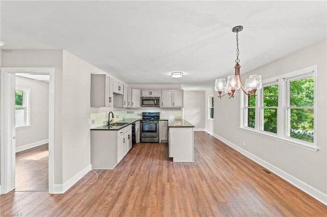212 Lakeview Dr E, Thomasville, NC 27360 - kitchen with appliances with stainless steel finishes, light wood finished floors, a chandelier, dark countertops, and decorative backsplash