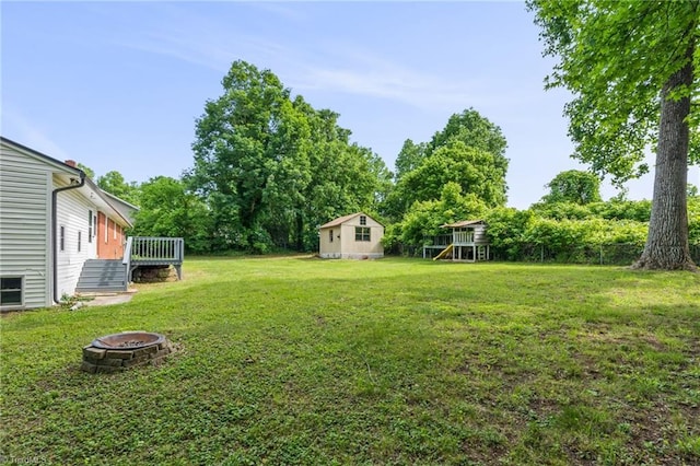 212 Lakeview Dr E, Thomasville, NC 27360 - view of green lawn with a fire pit, a deck, view of wooded area, and a storage shed