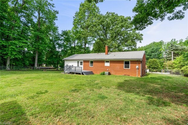 212 Lakeview Dr E, Thomasville, NC 27360 - rear view of property featuring a deck, a fenced backyard, brick siding, and a chimney