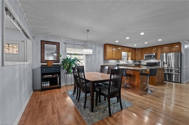 dining space featuring light hardwood / wood-style floors, ornamental molding, and a textured ceiling