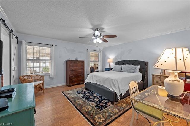 bedroom featuring a textured ceiling, ceiling fan, light wood-type flooring, and crown molding