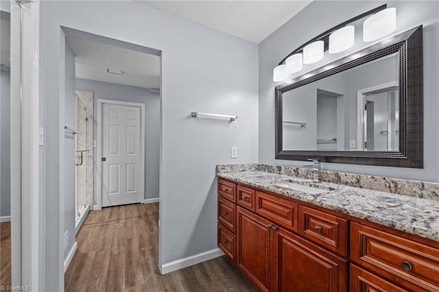 bathroom featuring hardwood / wood-style flooring, vanity, a textured ceiling, and walk in shower