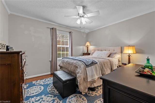 bedroom with a textured ceiling, ceiling fan, wood-type flooring, and ornamental molding