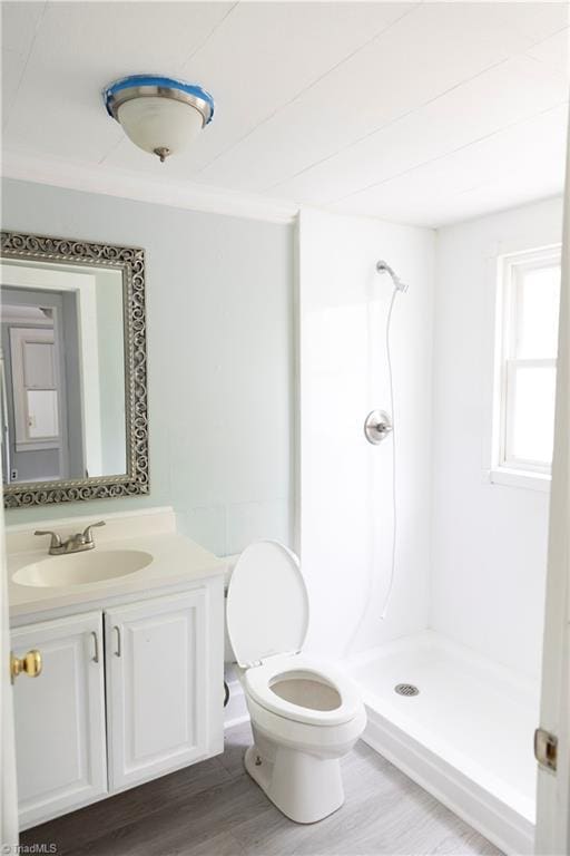 full bathroom with a shower stall, wood finished floors, vanity, toilet, and ornamental molding