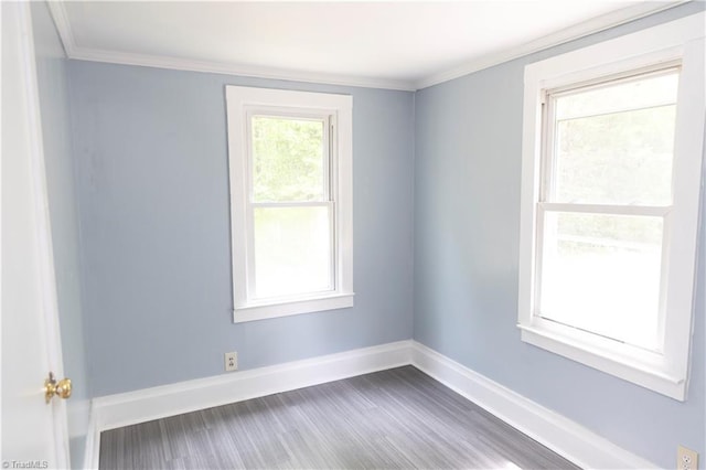 spare room featuring crown molding, baseboards, and wood finished floors