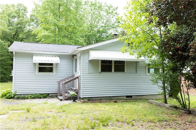 back of house with a lawn, a chimney, crawl space, and entry steps