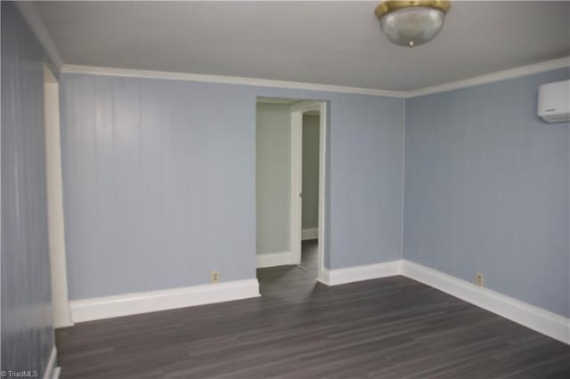 spare room with crown molding, dark wood-style flooring, baseboards, and a wall unit AC