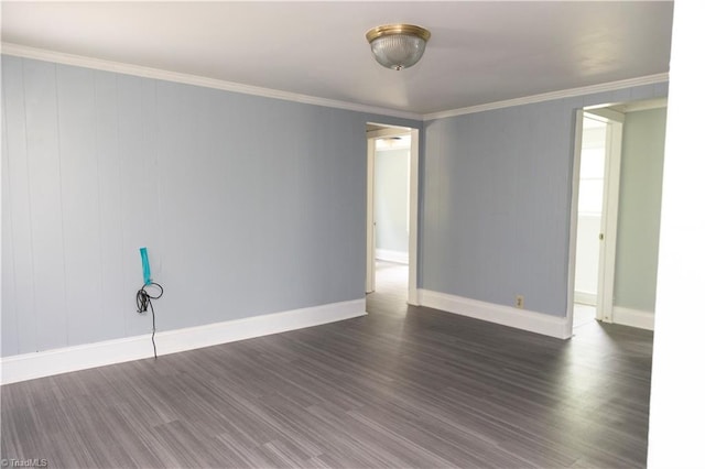spare room featuring crown molding, dark wood-style flooring, and baseboards