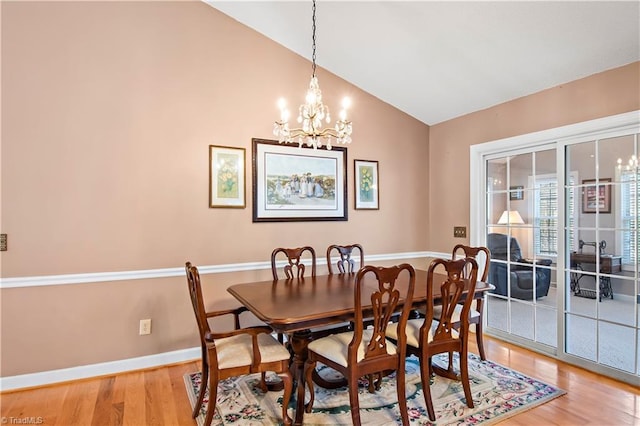 dining room with a chandelier, light wood-type flooring, vaulted ceiling, and baseboards