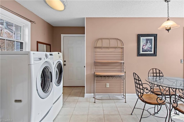 washroom with light tile patterned floors, laundry area, a textured ceiling, and washing machine and dryer