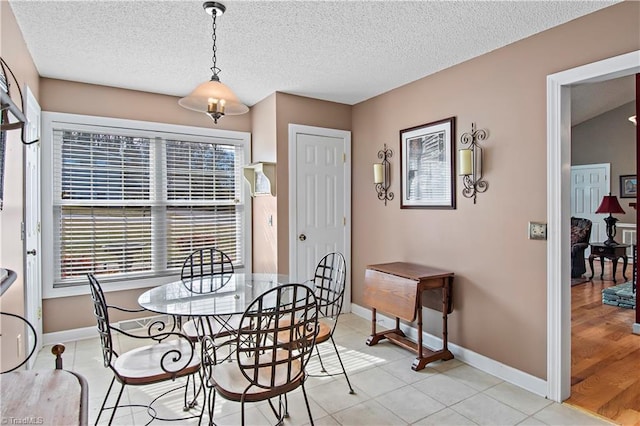 dining room with light tile patterned flooring, a textured ceiling, and baseboards