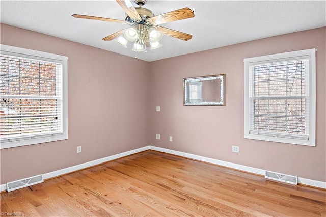 unfurnished room featuring a wealth of natural light, visible vents, and baseboards