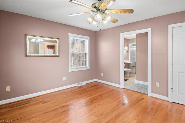 unfurnished room with light wood finished floors, a ceiling fan, visible vents, and baseboards