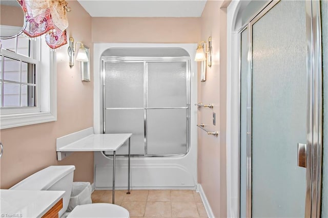 bathroom featuring toilet, combined bath / shower with glass door, vanity, baseboards, and tile patterned floors