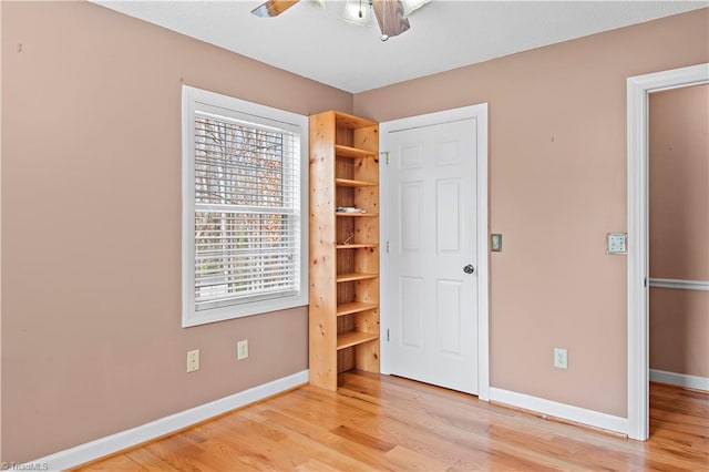 unfurnished bedroom with a ceiling fan, light wood-style flooring, and baseboards