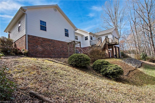 view of side of home featuring stairs, brick siding, and a deck