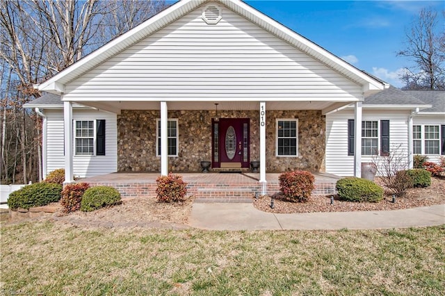 view of front of home with stone siding, a porch, and a front lawn