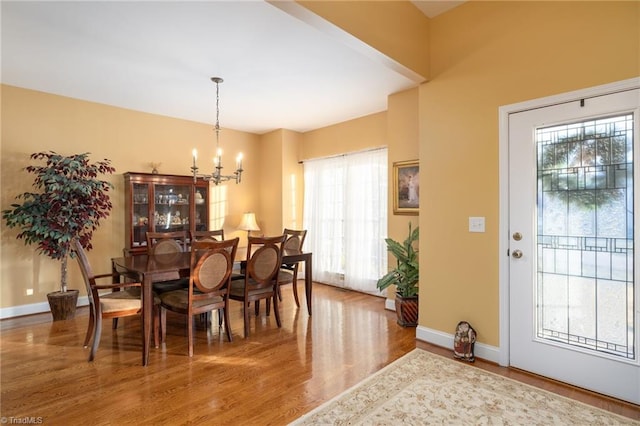 dining room with a notable chandelier, plenty of natural light, and wood-type flooring