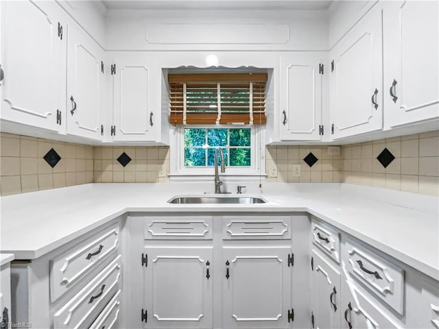 kitchen featuring sink, backsplash, and white cabinetry