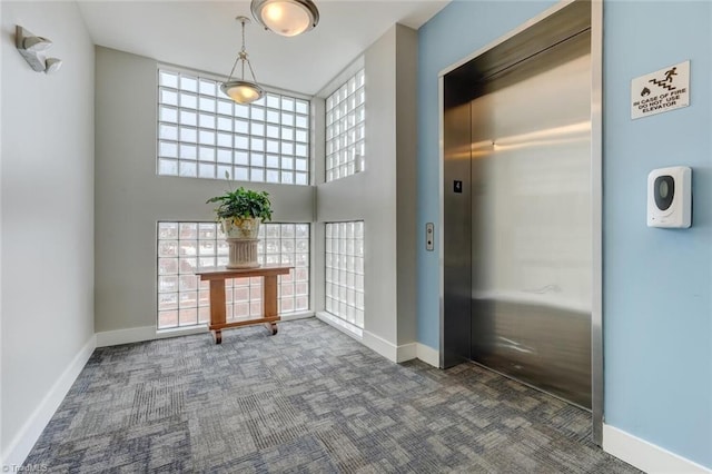 interior space with carpet floors, elevator, and baseboards