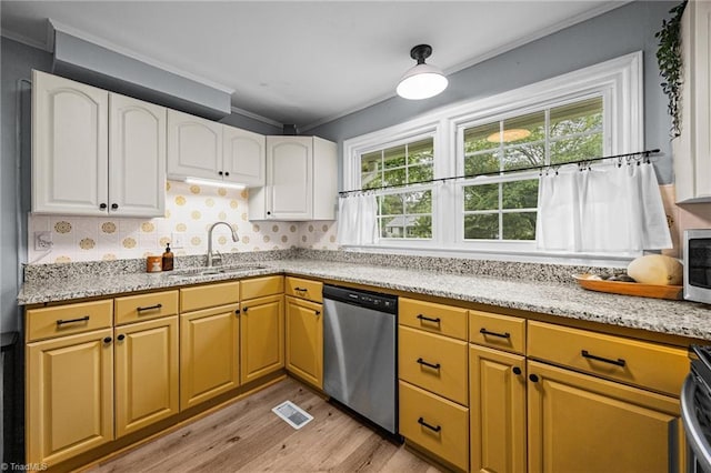 kitchen featuring stainless steel appliances, a sink, light wood finished floors, crown molding, and light stone countertops
