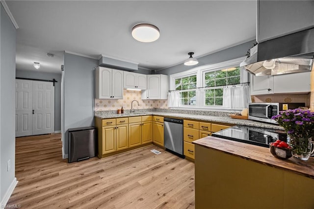 kitchen featuring stainless steel appliances, a sink, light wood-style floors, tasteful backsplash, and baseboards