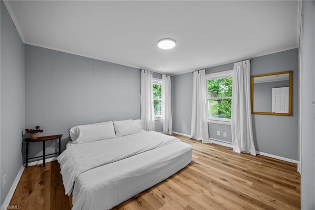 bedroom featuring wood finished floors, baseboards, and crown molding