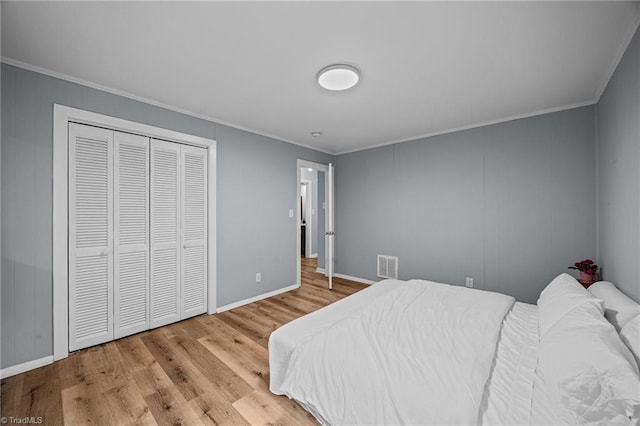 bedroom with ornamental molding, wood finished floors, baseboards, and a closet