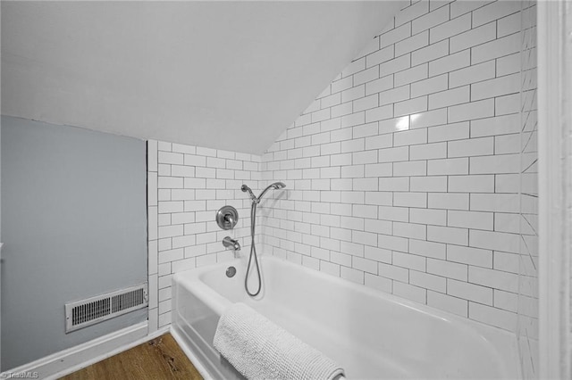 bathroom featuring lofted ceiling, a tub, wood finished floors, baseboards, and a shower