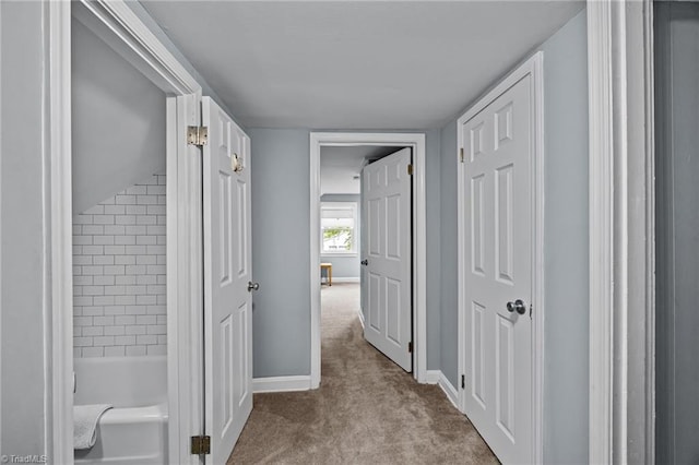 hall featuring carpet flooring and baseboards