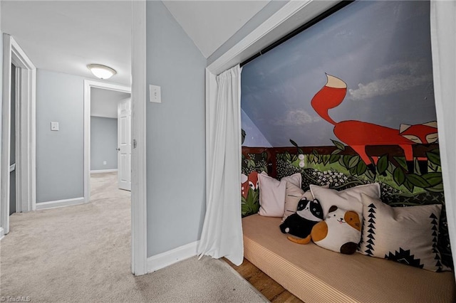 hall featuring lofted ceiling, baseboards, and carpet flooring