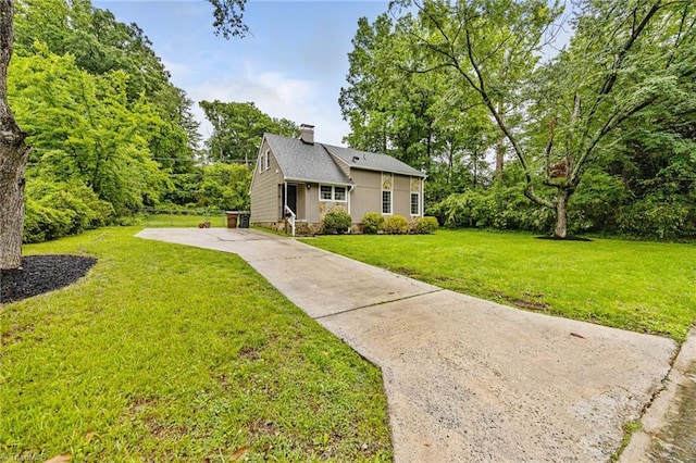 view of front of property featuring concrete driveway, a chimney, and a front yard