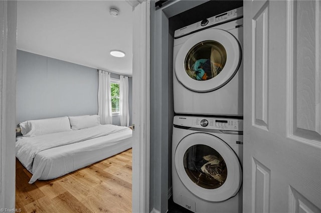 laundry room with stacked washer / dryer and wood finished floors