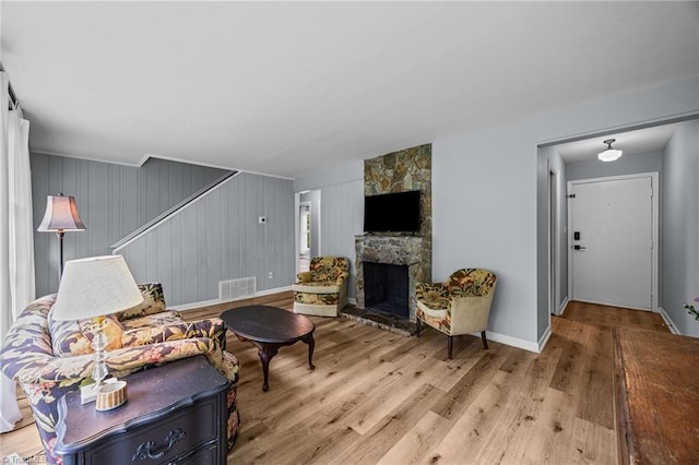 living room featuring a stone fireplace, wood finished floors, and baseboards