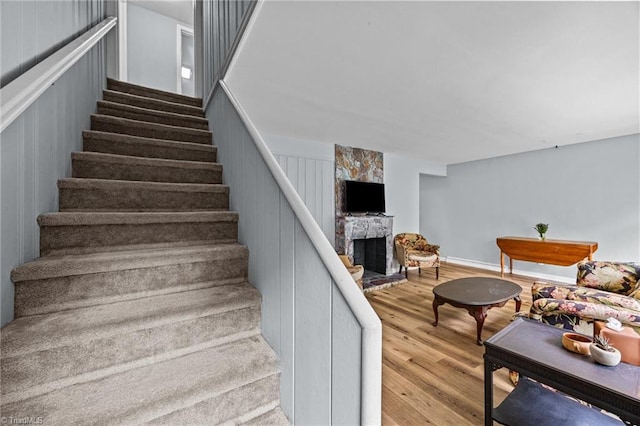 staircase with a fireplace and wood finished floors