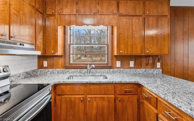 kitchen featuring light stone countertops, sink, and stainless steel range with electric cooktop