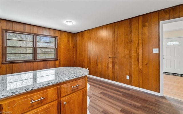 kitchen with light stone countertops, hardwood / wood-style floors, and wood walls